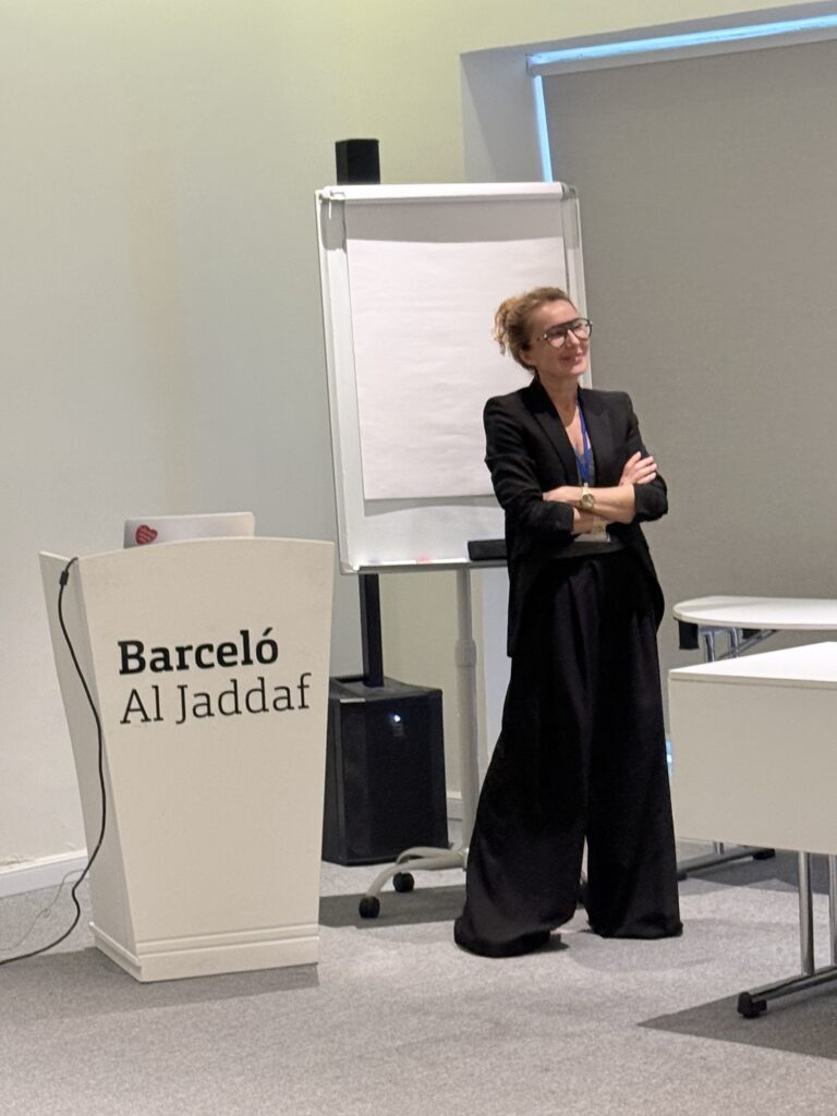 A woman stands beside the Barceló Al Jaddaf lectern and a flip chart.