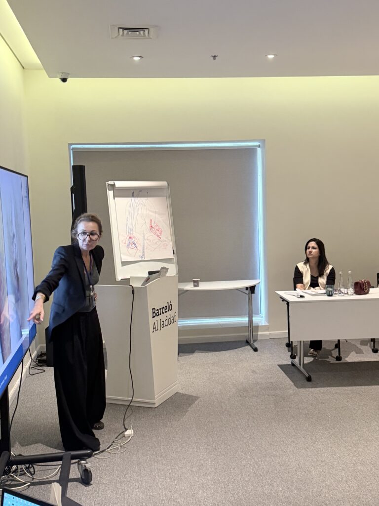 A presenter gestures toward a display during a classroom session.