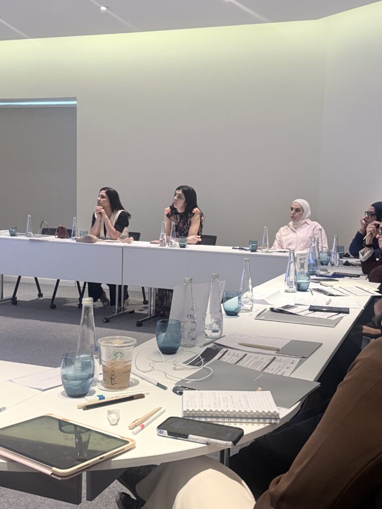 Participants seated around tables with notes and devices.