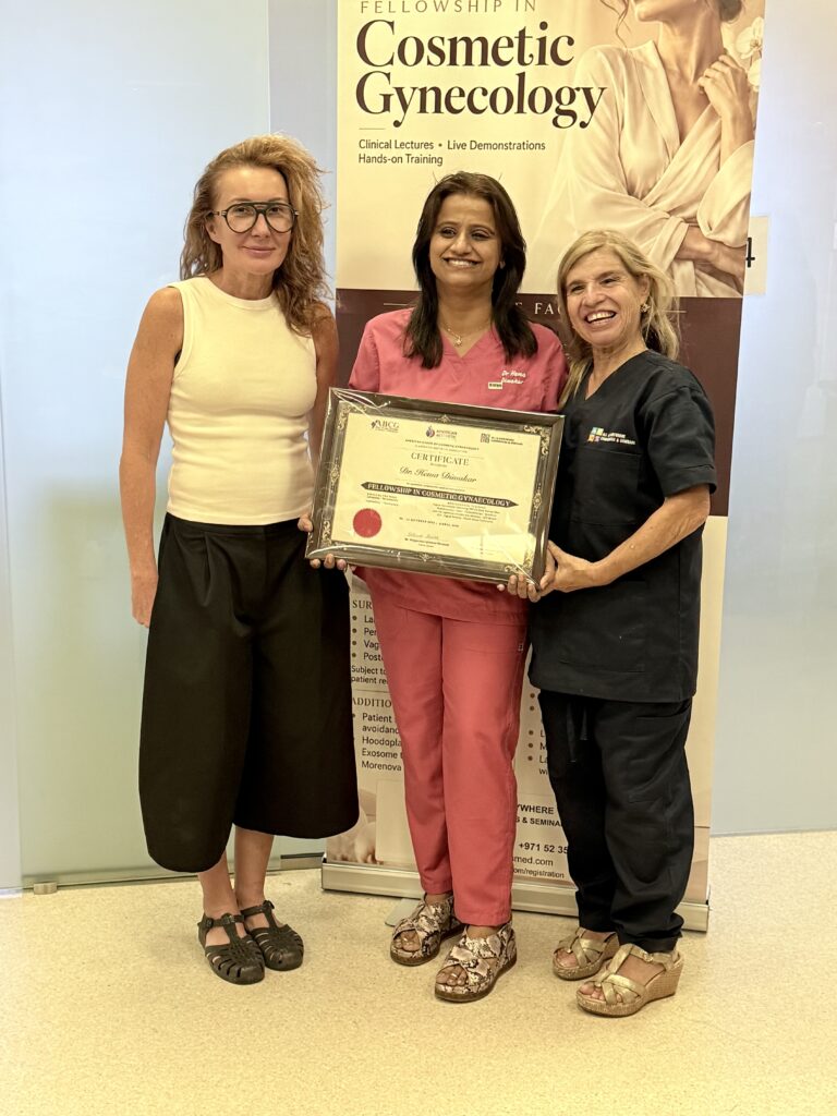 A woman in pink scrubs displays her course certificate beside two women.